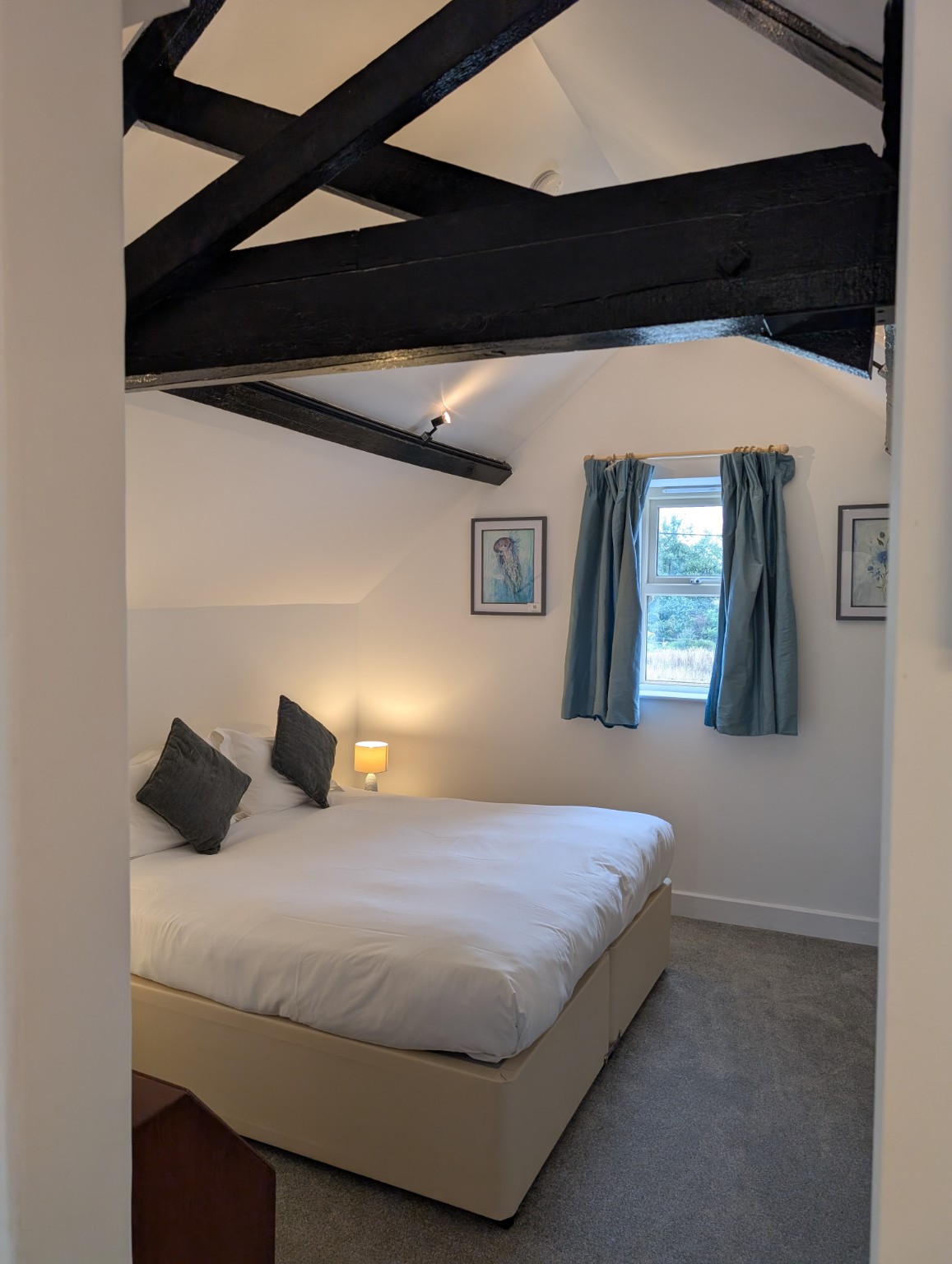 The Hayloft: a bedroom under the beams, with a window over the fields.