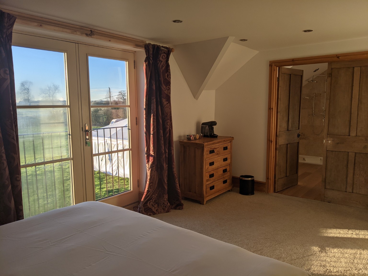 Robin: the Juliet-balcony glazed doors and burgundy curtains, looking out over the fields.